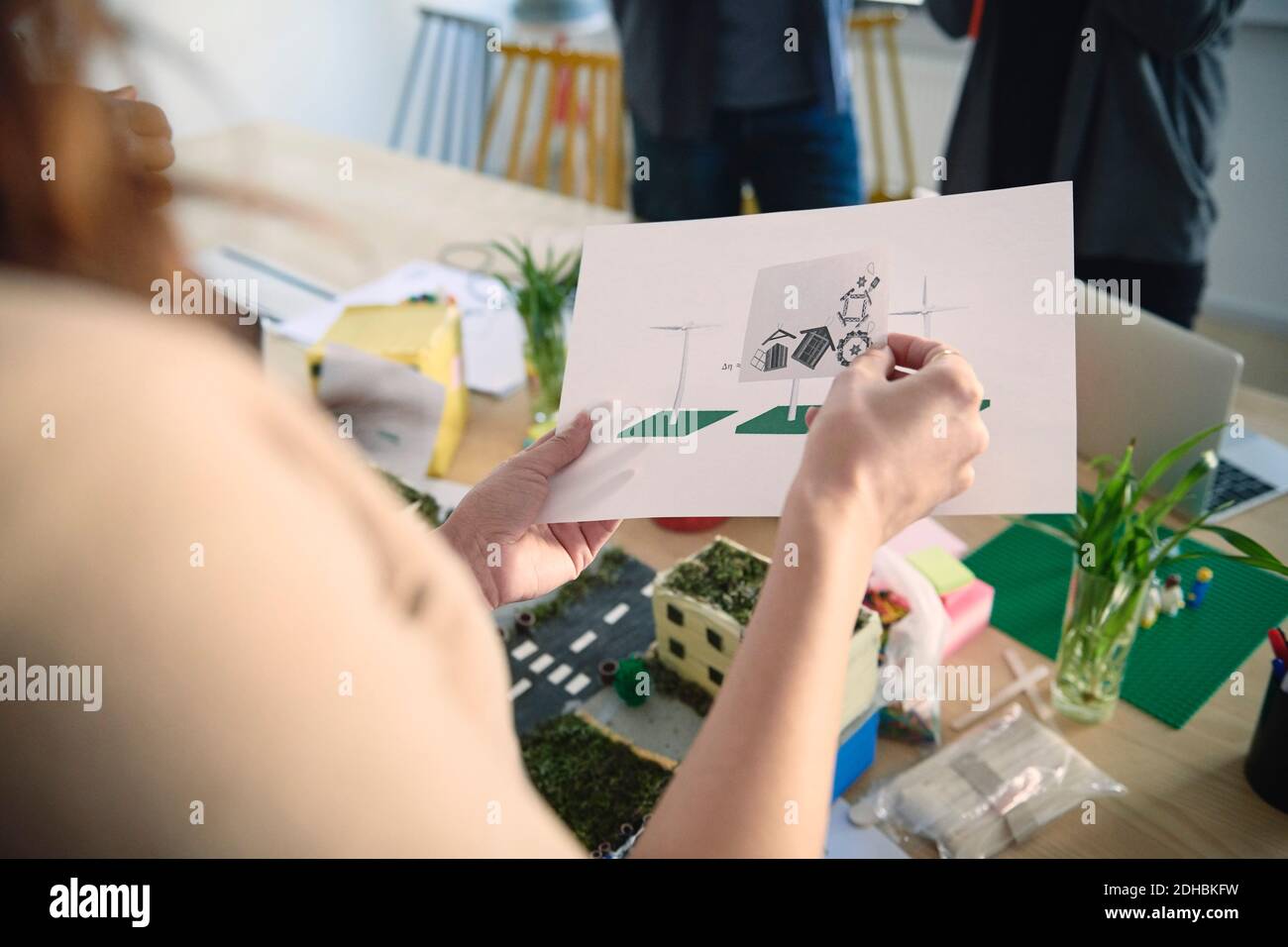 Immagine ritagliata di un ingegnere femminile che tiene i diagrammi al tavolo in ufficio Foto Stock