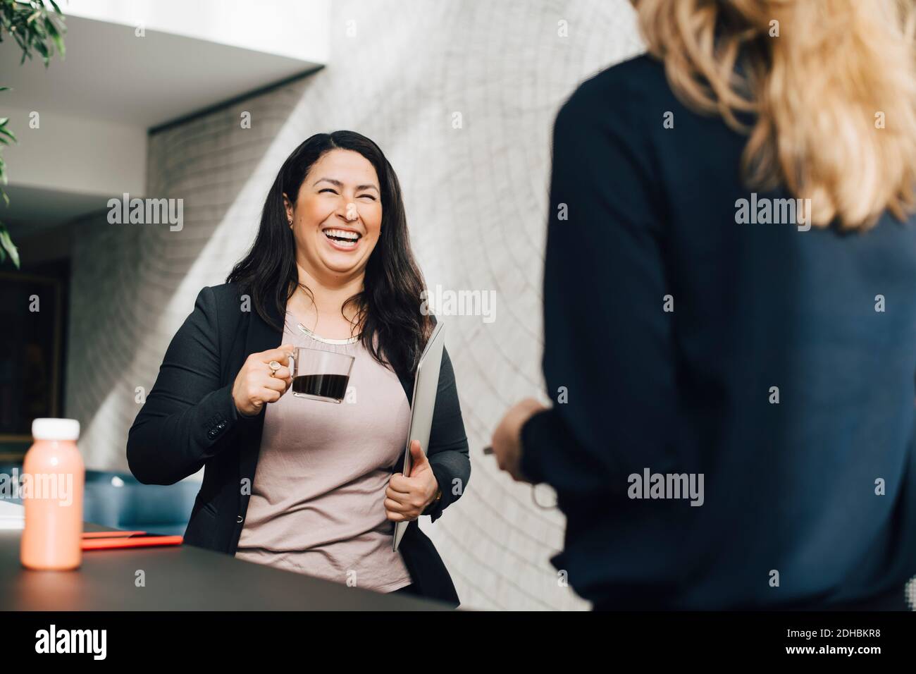 Donna d'affari sorridente che ha il caffè mentre parla con il collega alla conferenza Foto Stock