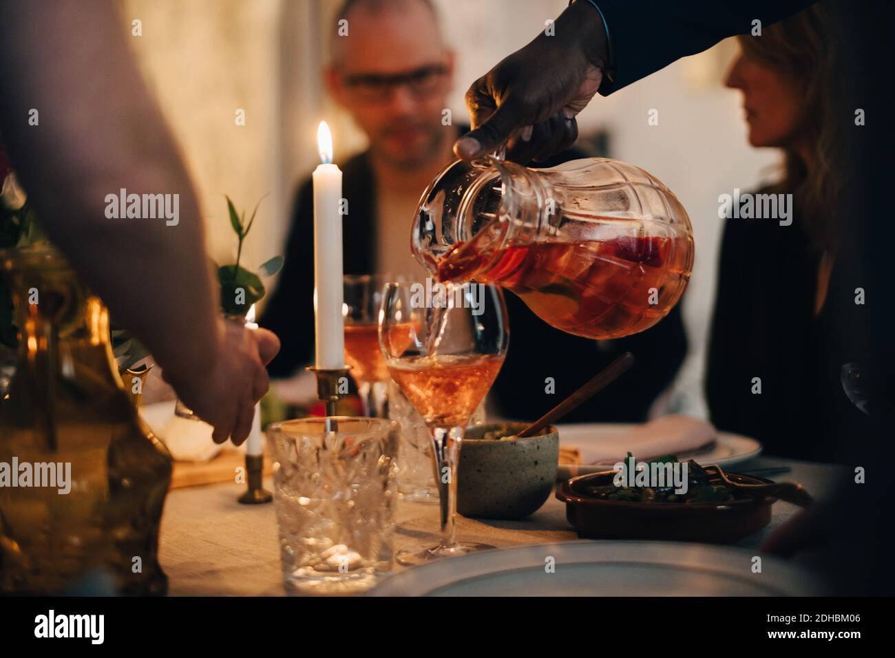 Mano di uomo tagliata che beve agli amici a cena festa a casa Foto Stock