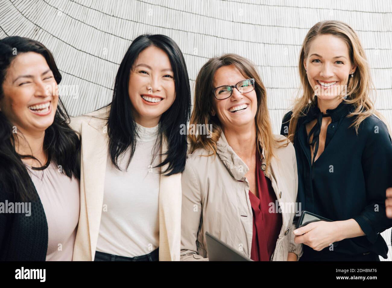 Ritratto di felici donne multietniche professionisti del business in piedi contro il muro Foto Stock