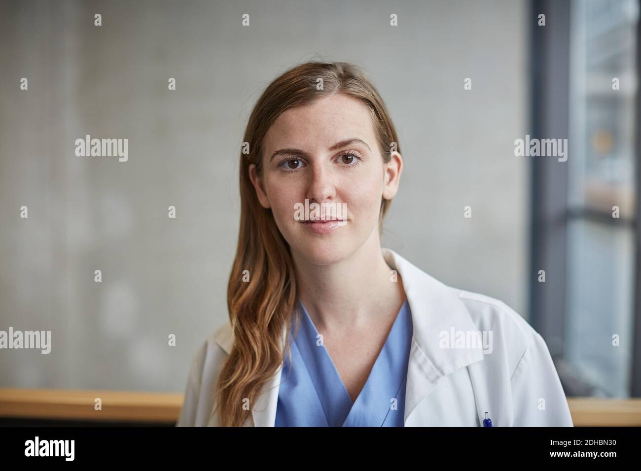 Ritratto di fidato medico femminile medio adulto in piedi in corridoio in ospedale Foto Stock