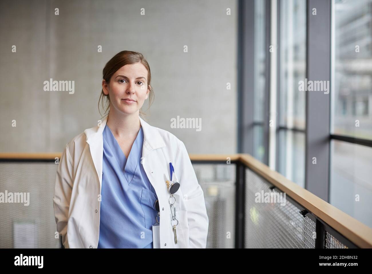 Ritratto di sicuro medico femminile medio adulto da finestra in corridoio all'ospedale Foto Stock