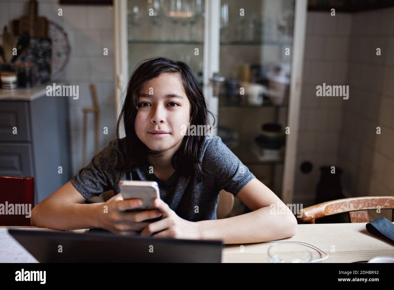 Ritratto di ragazzo sorridente che usa il telefono cellulare per i compiti a casa casa Foto Stock