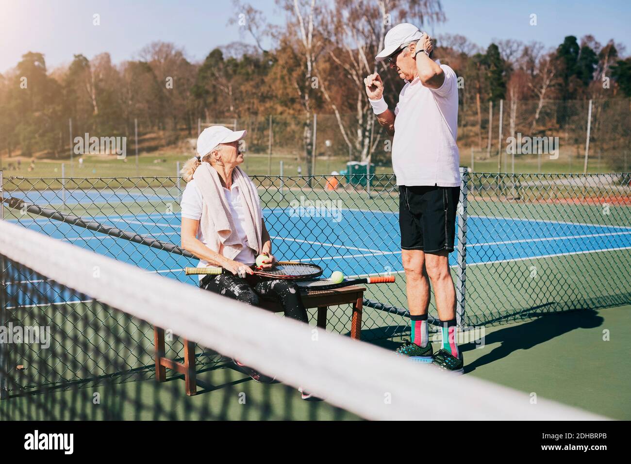 Uomo anziano che parla con un amico al campo da tennis in estate Foto Stock
