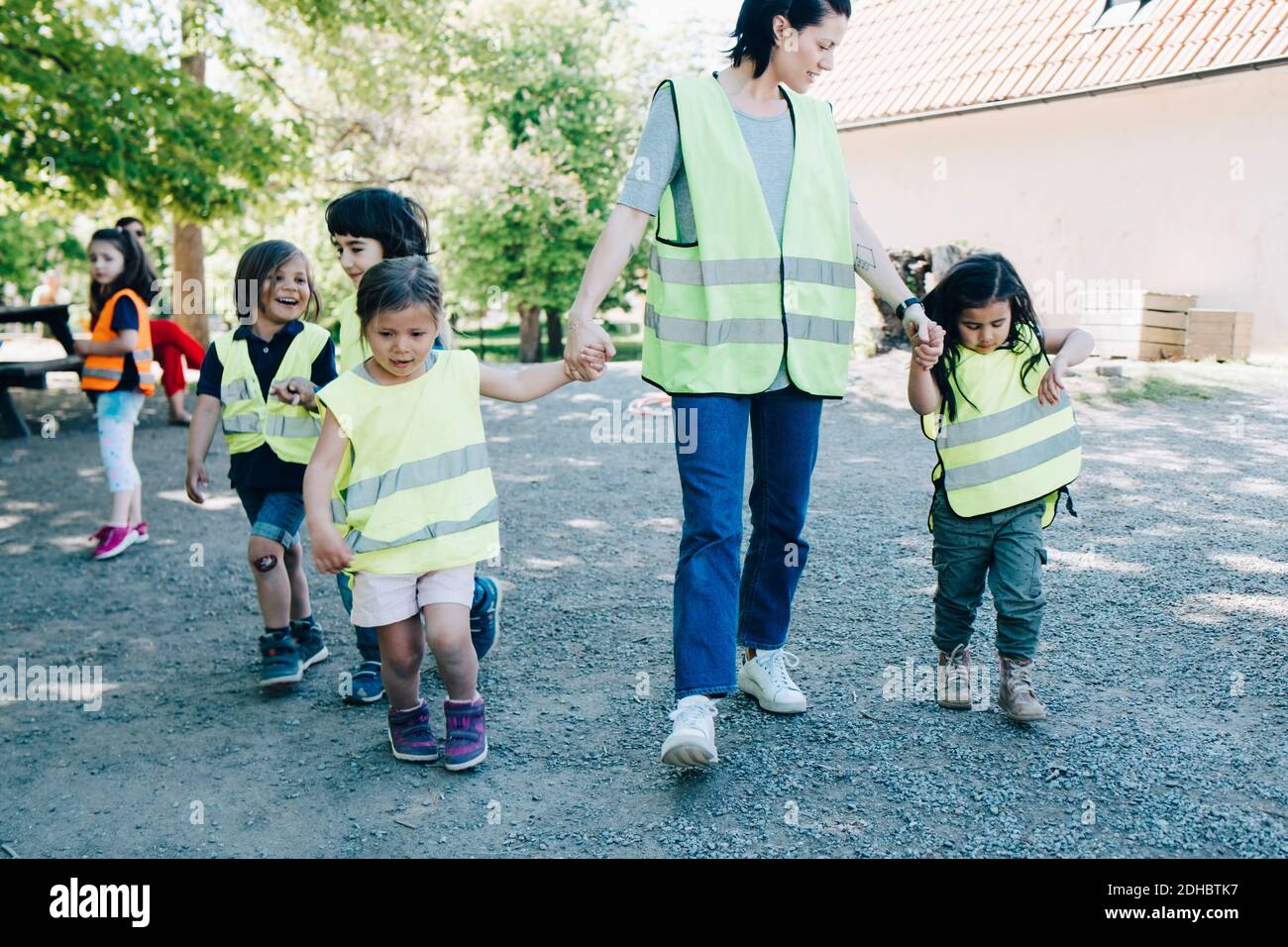 Insegnante che cammina con gli studenti nel parco giochi presso l'asilo Foto Stock