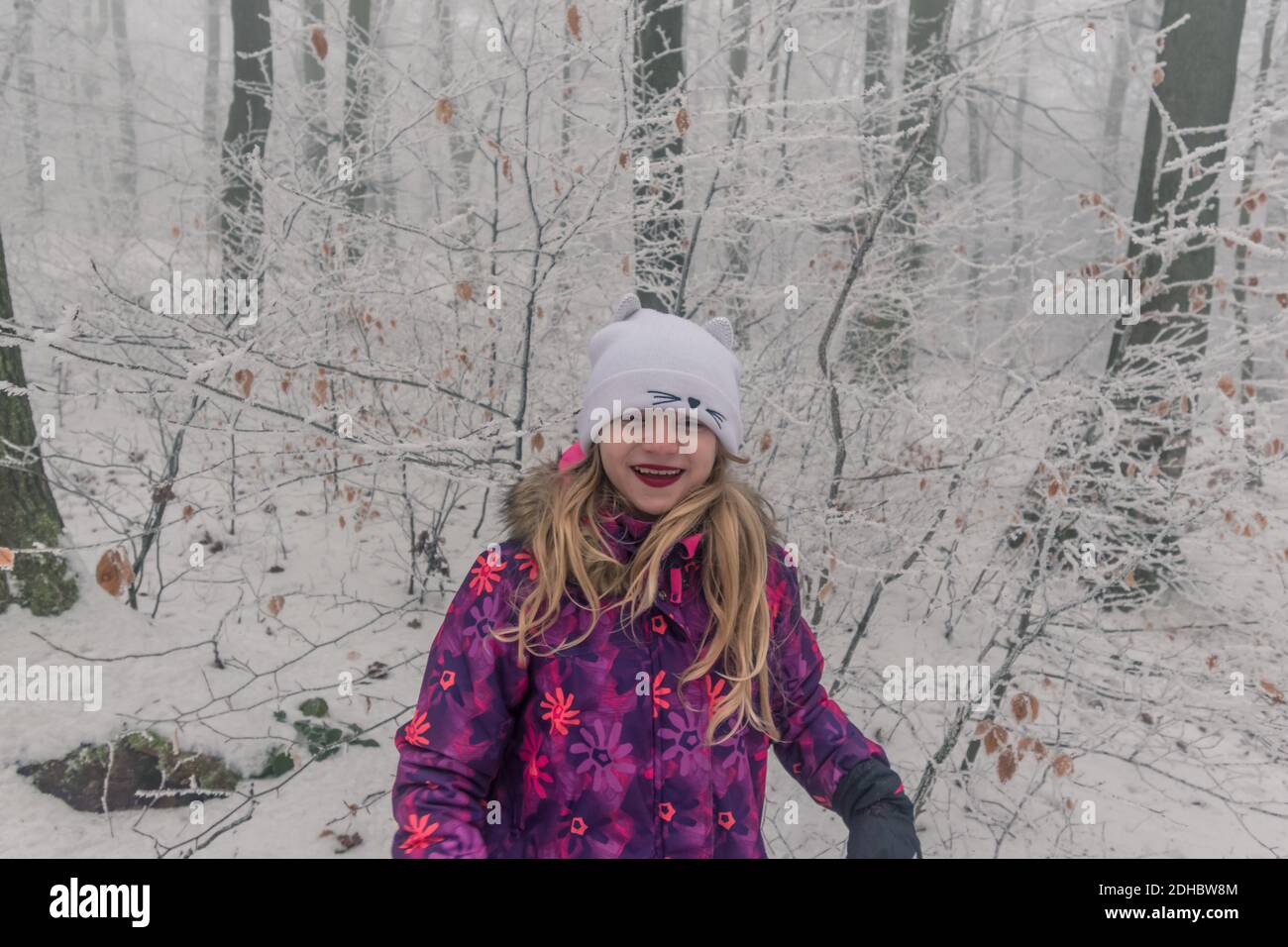 ragazza felice con lunghi capelli biondi nel bosco invernale Foto Stock