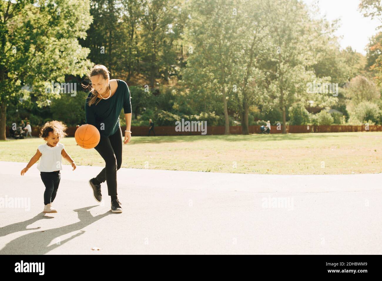 Madre e figlia giocano con la palla al parco in città Foto Stock