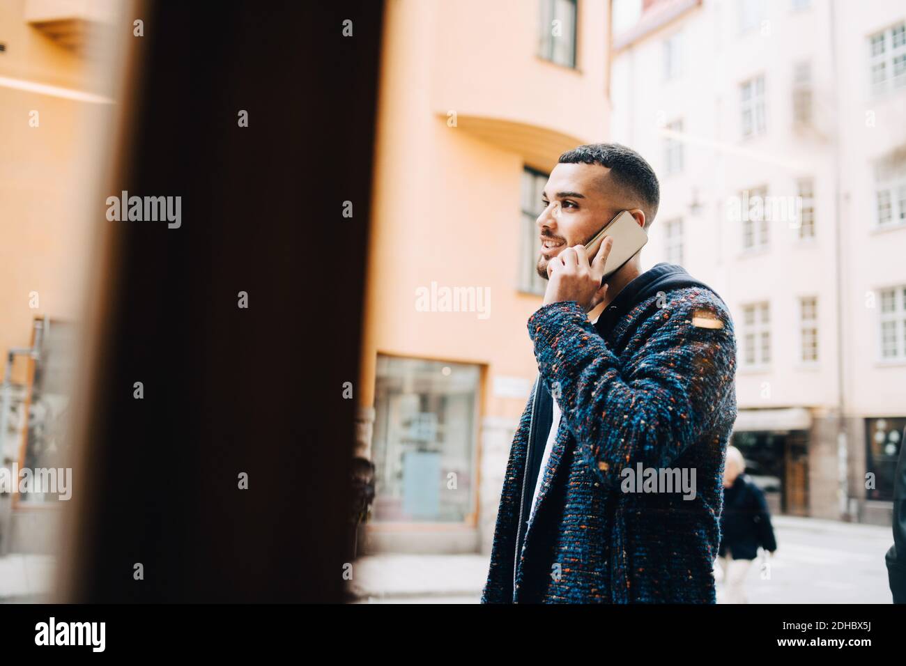 Giovane uomo d'affari che parla su smartphone visto attraverso la finestra Foto Stock