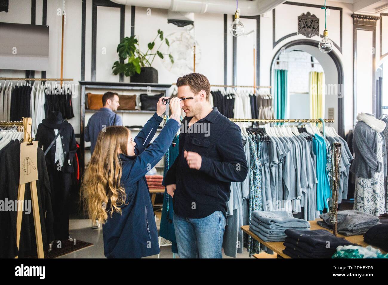 Figlia che cerca gli occhiali sul padre in boutique Foto Stock