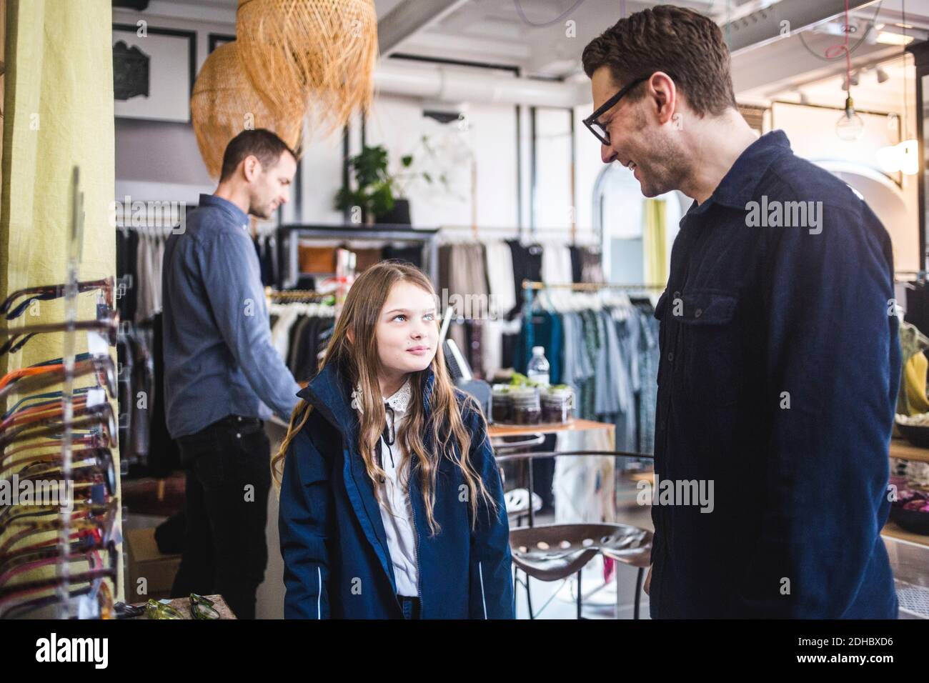 Sorridente padre che indossa occhiali mentre si guarda la figlia carina dentro boutique Foto Stock