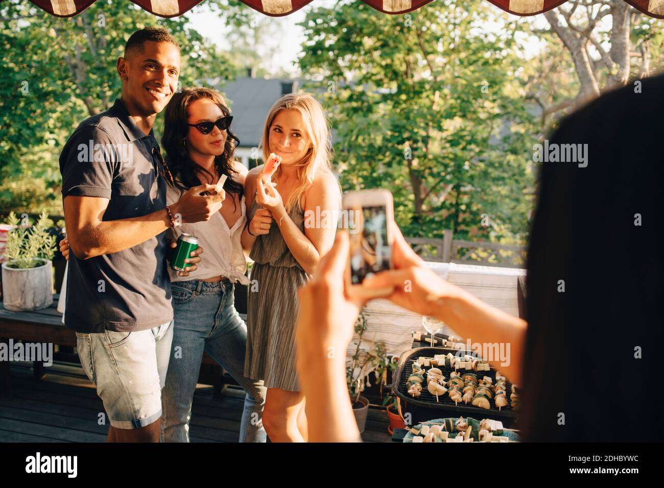 Donna che fotografa amici sorridenti su smartphone mentre ti godi cena Foto Stock