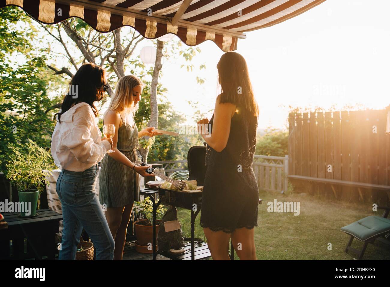 Amici femminili che parlano mentre preparano il cibo sulla griglia del barbecue dentro cena Foto Stock