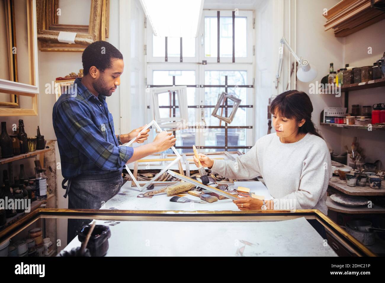 Artisti maschili e femminili che fanno cornice al banco di lavoro dentro negozio Foto Stock