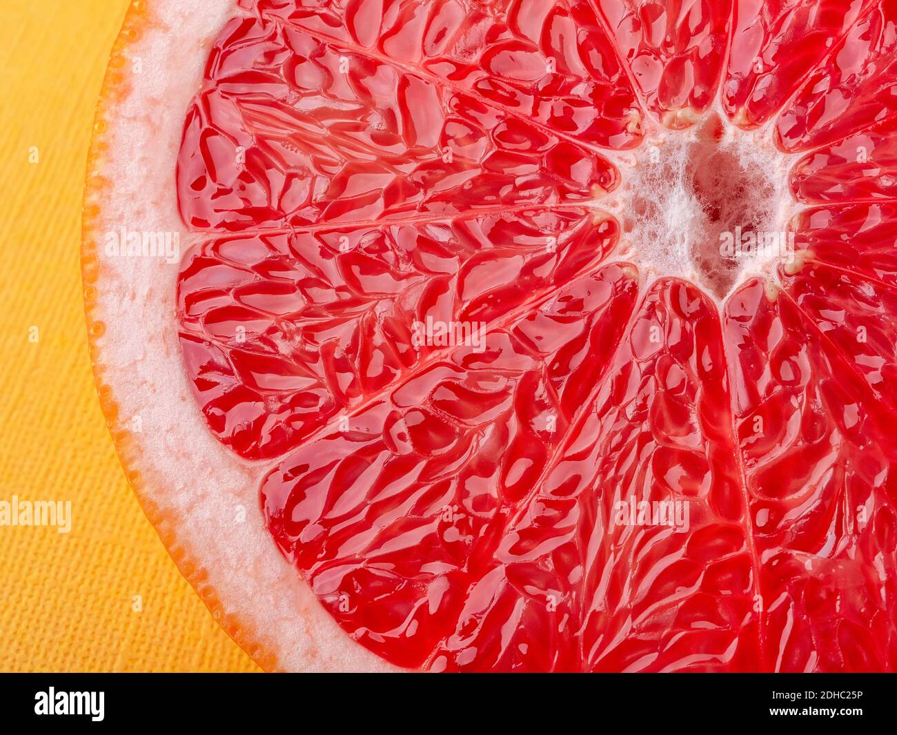 Fetta di pompelmo succoso maturo su una macro di sfondo giallo. Ingrediente per dolci di frutta. Cibo vegetariano gustoso, dieta dimagrante e vitamine. Foto Stock