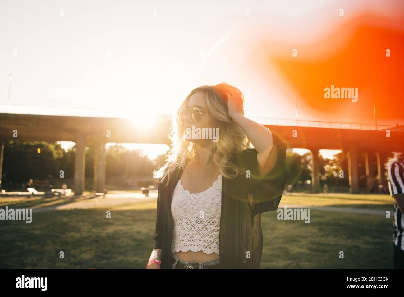 Giovane donna alla moda che guarda via l'evento contro il cielo durante giorno di sole Foto Stock