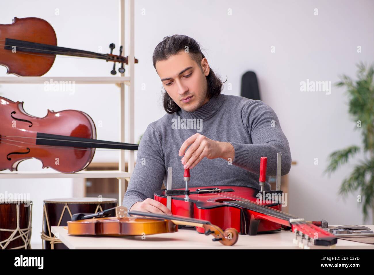 Giovane uomo riparatore che ripara la chitarra Foto Stock