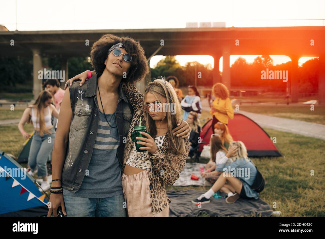 Amici alla moda con persone in background all'evento musicale Foto Stock