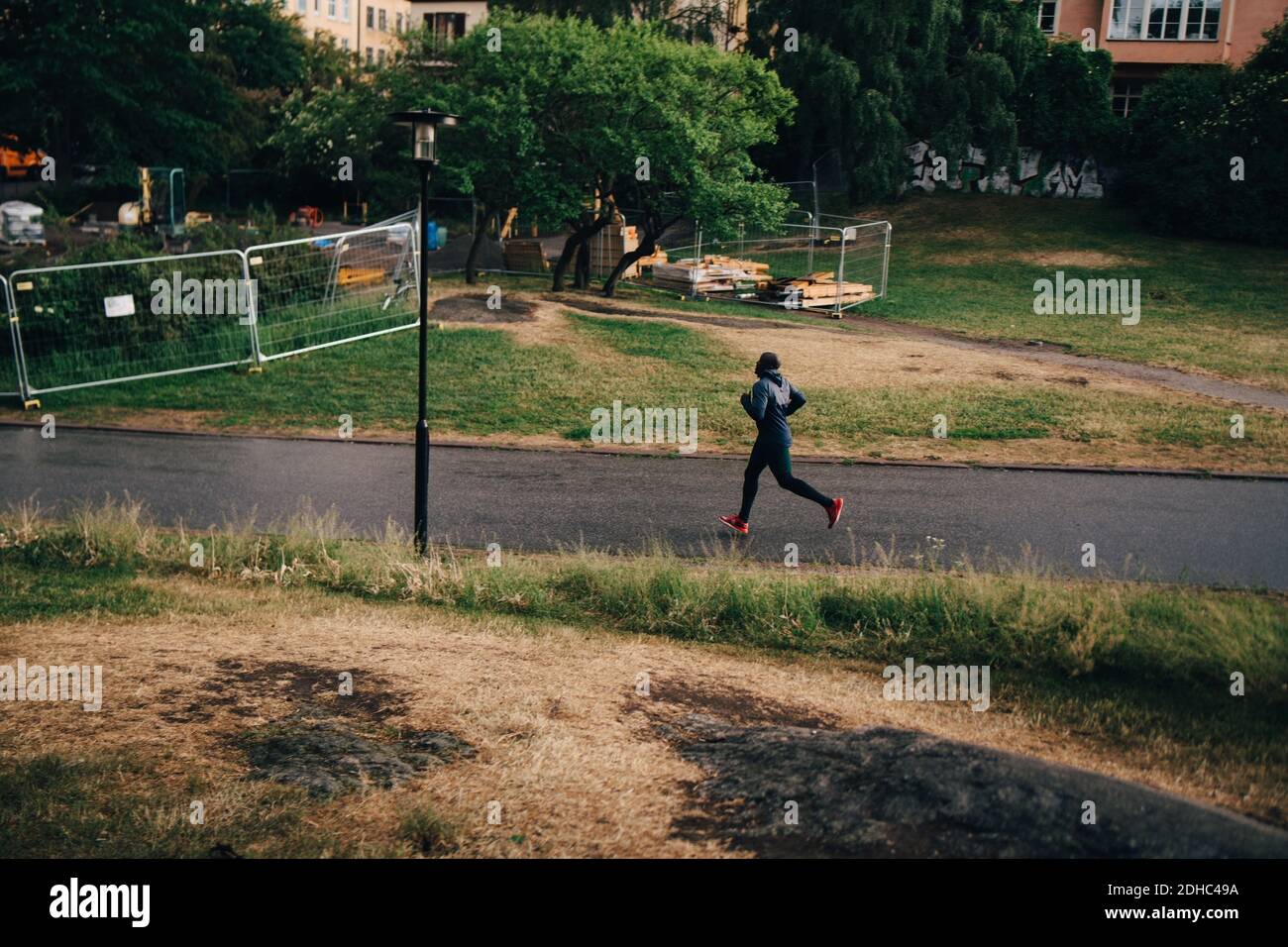 Intera lunghezza di atleta maschile jogging su strada in città Foto Stock