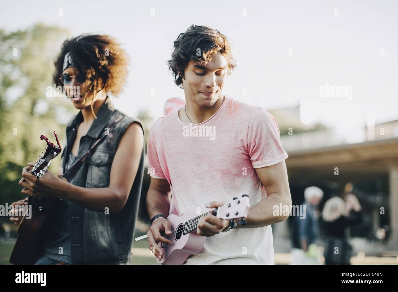 Felici giovani che suonano ukulele al concerto di musica in estate Foto Stock