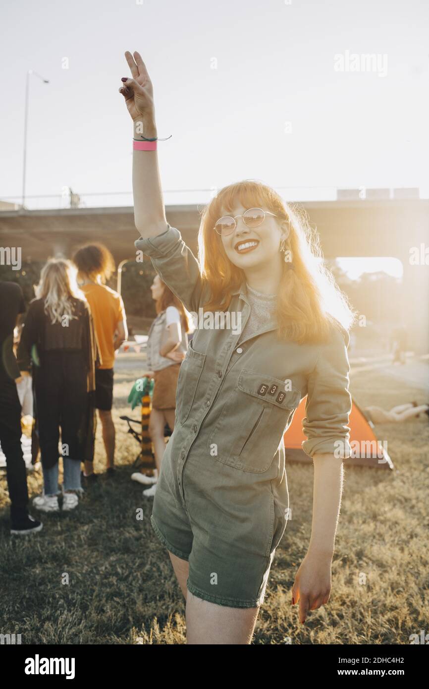 Felice giovane donna che gesturing mentre si sta in piedi sul prato Foto Stock