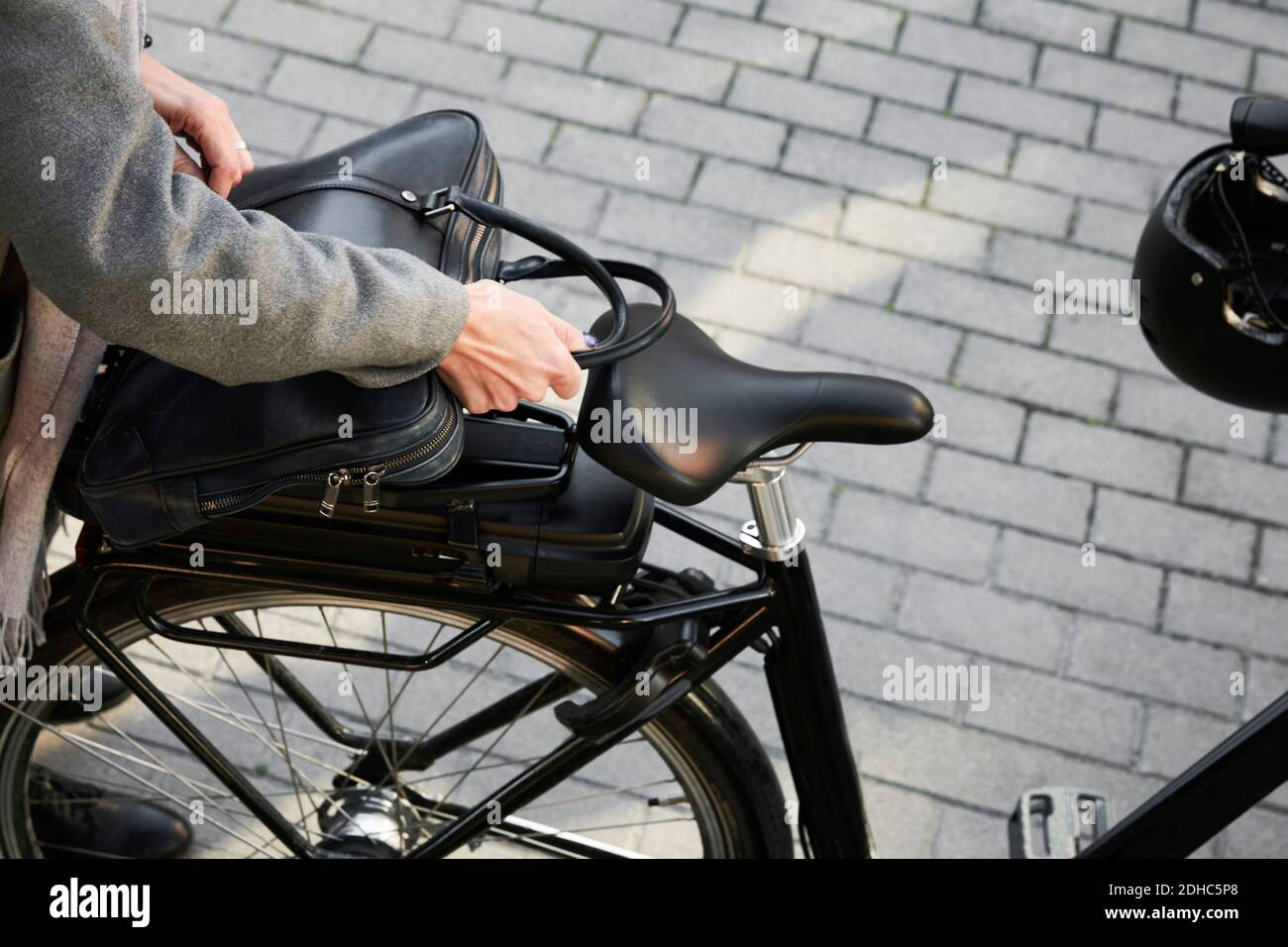 Immagine ritagliata della borsa di posizionamento donna sulla bicicletta elettrica in città Foto Stock