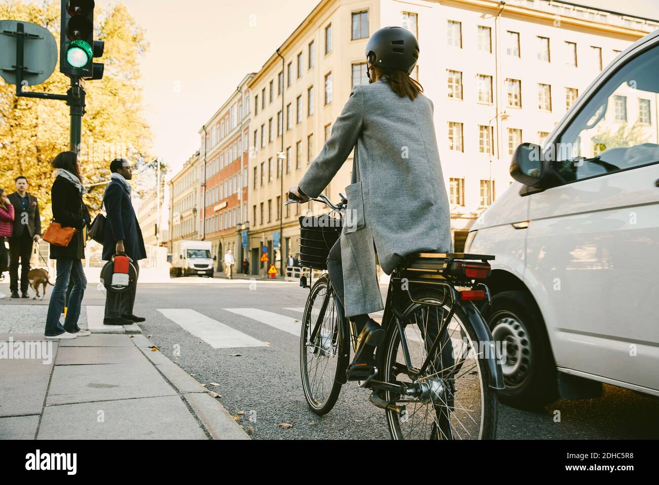 Vista posteriore della donna che guida in bicicletta elettrica in auto via in città Foto Stock