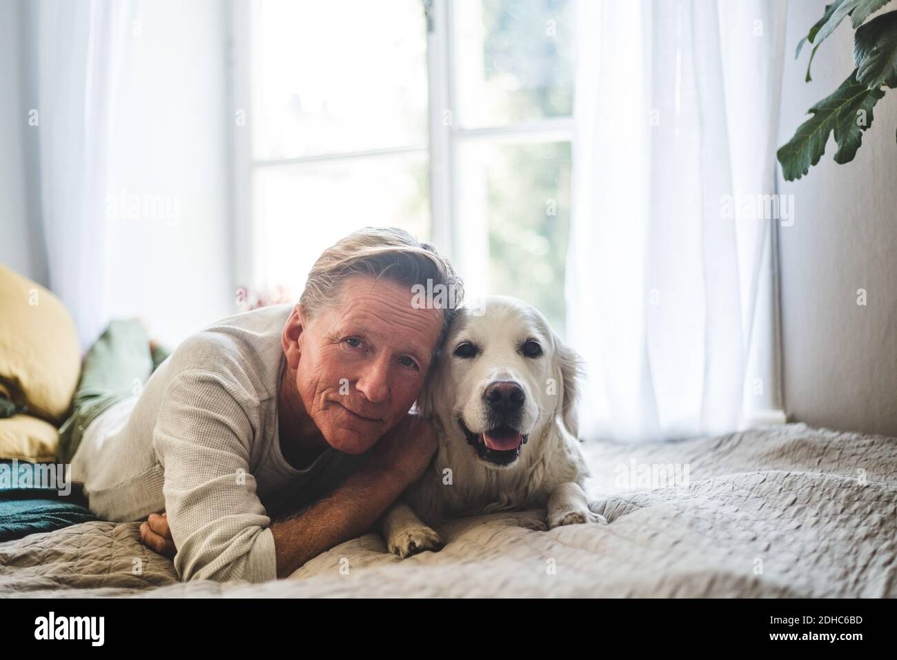 Primo piano ritratto di uomo anziano e cane sdraiato sul letto a casa Foto Stock