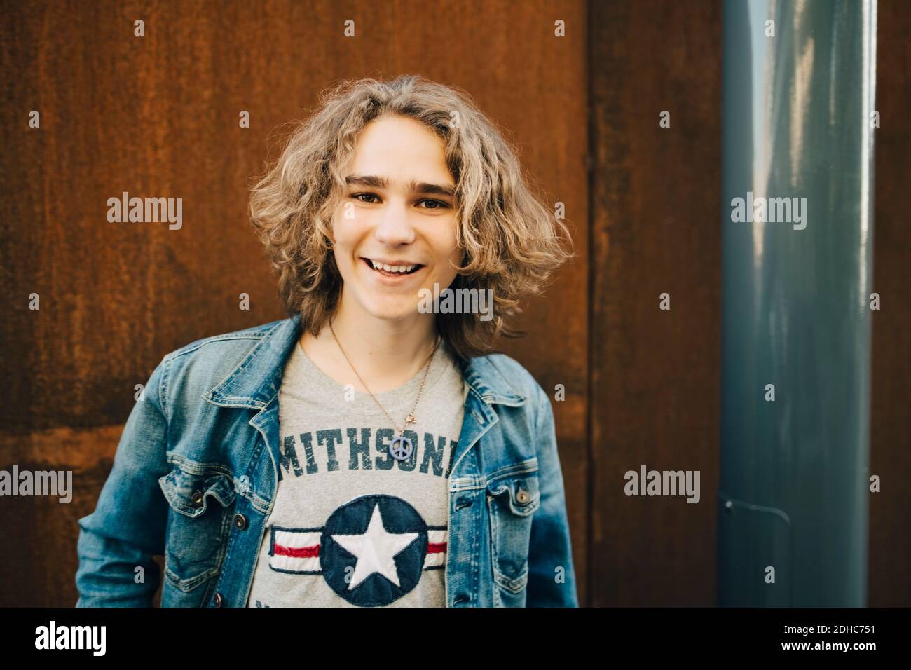 Ritratto di un giovane sorridente che indossa una giacca in denim in città Foto Stock