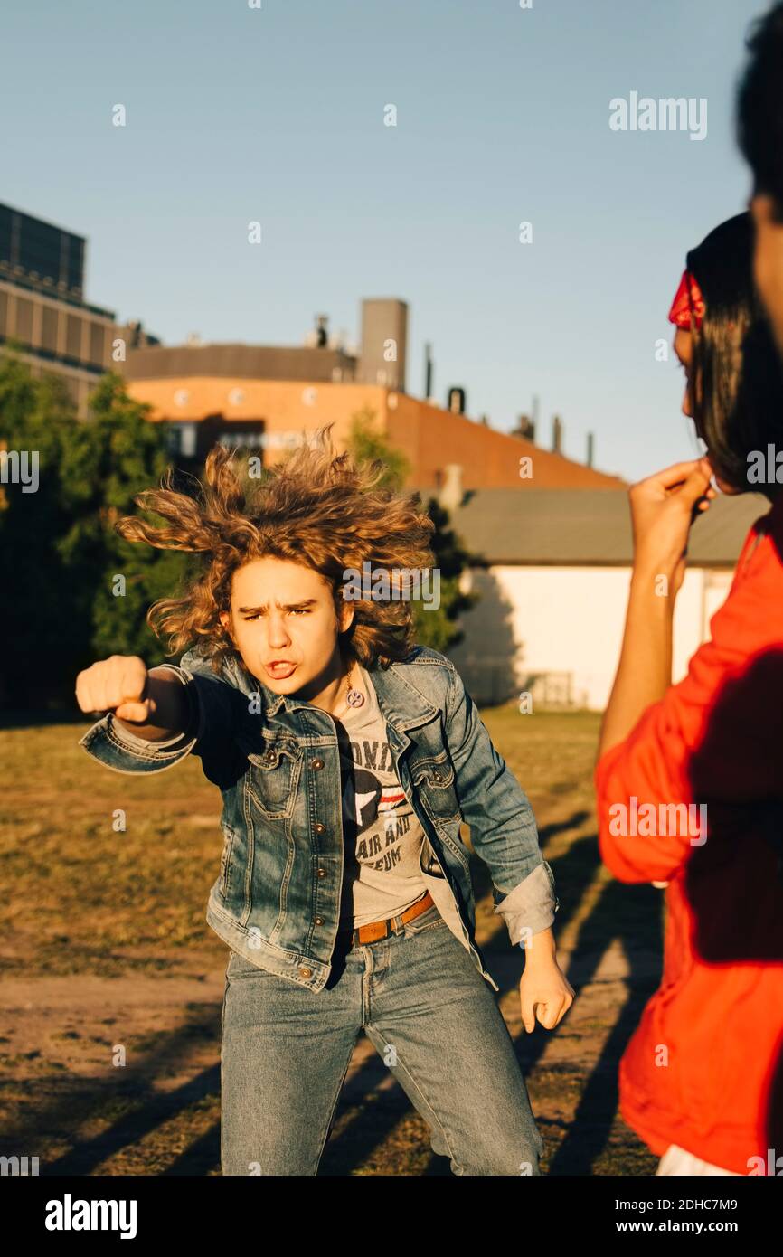 Amico che guarda il giovane uomo che gestura sul campo durante il sole giorno Foto Stock