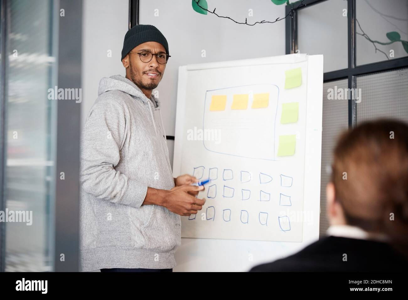 Imprenditore maschile che dà la presentazione su lavagna durante la riunione in ufficio Foto Stock