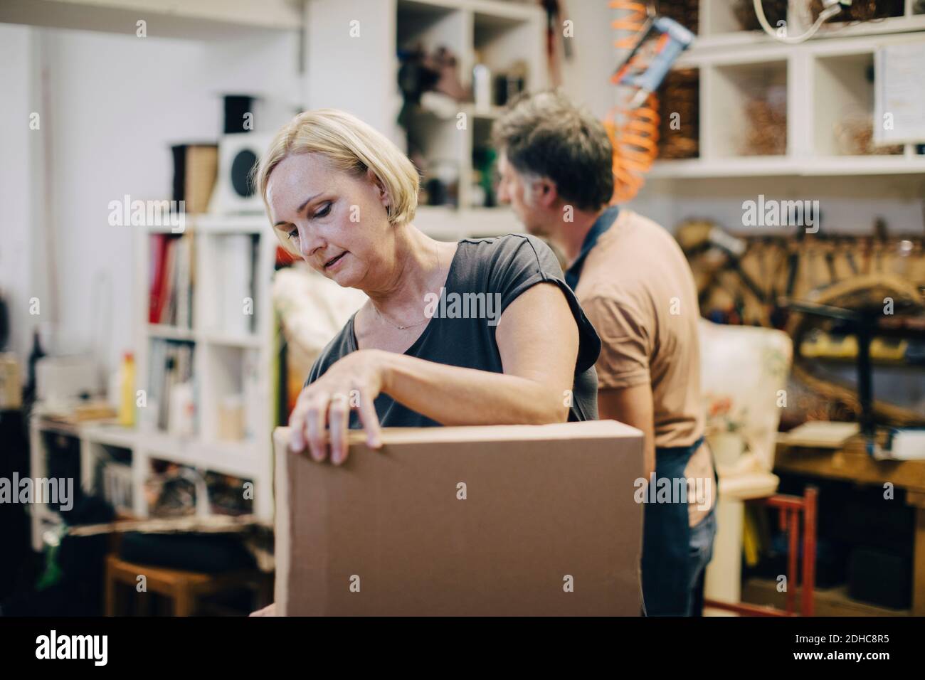 Artigiano femminile con scatola di cartone in officina Foto Stock