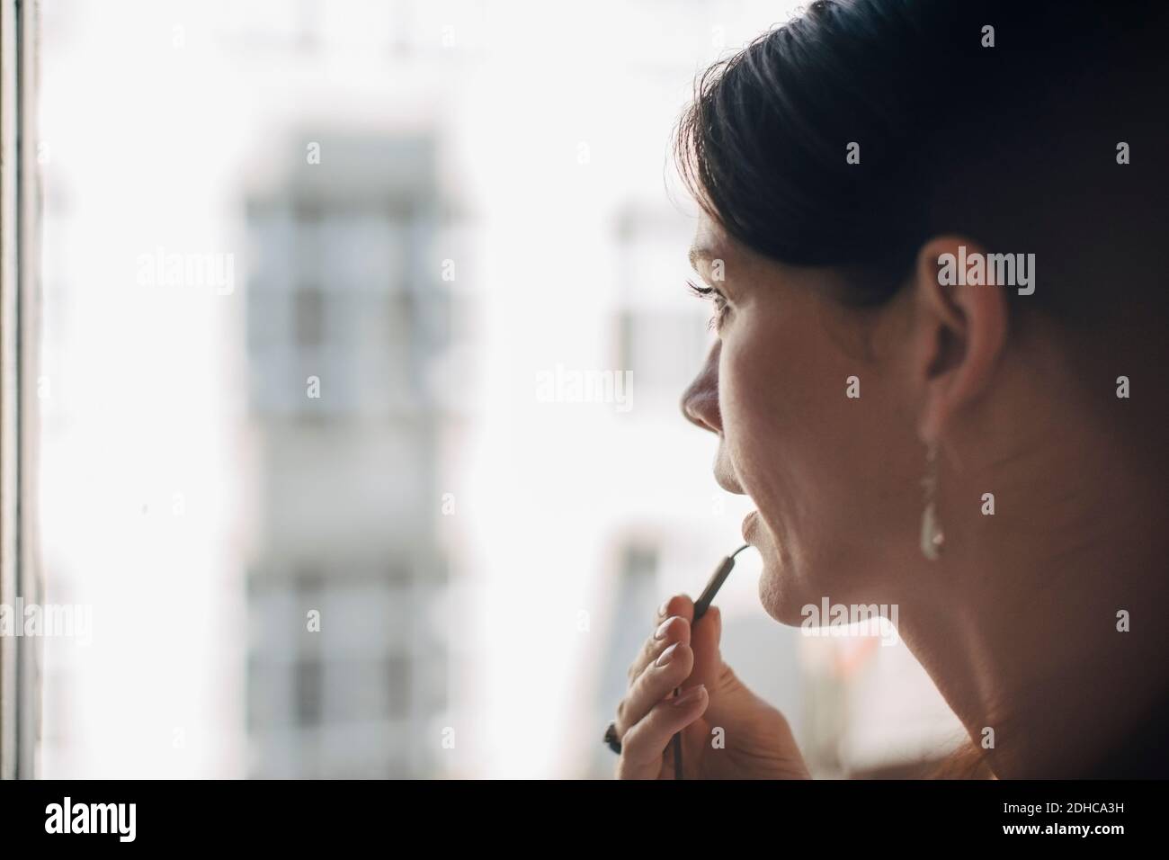 Professionista professionale creativo che parla attraverso gli auricolari dalla finestra in ufficio Foto Stock