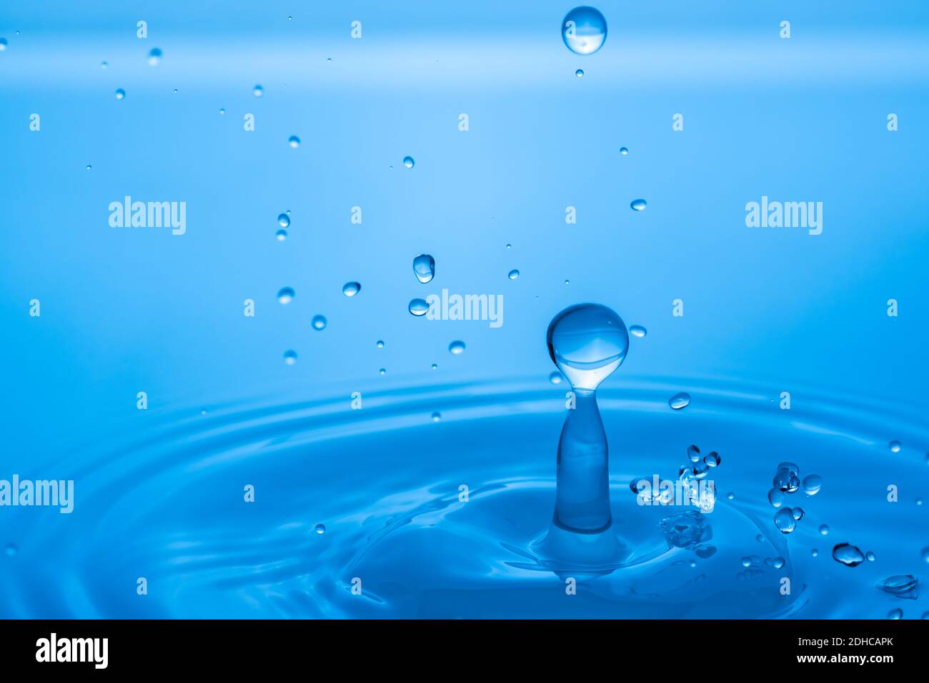 Gocce d'acqua che spruzzano sulla superficie blu dell'acqua Foto Stock