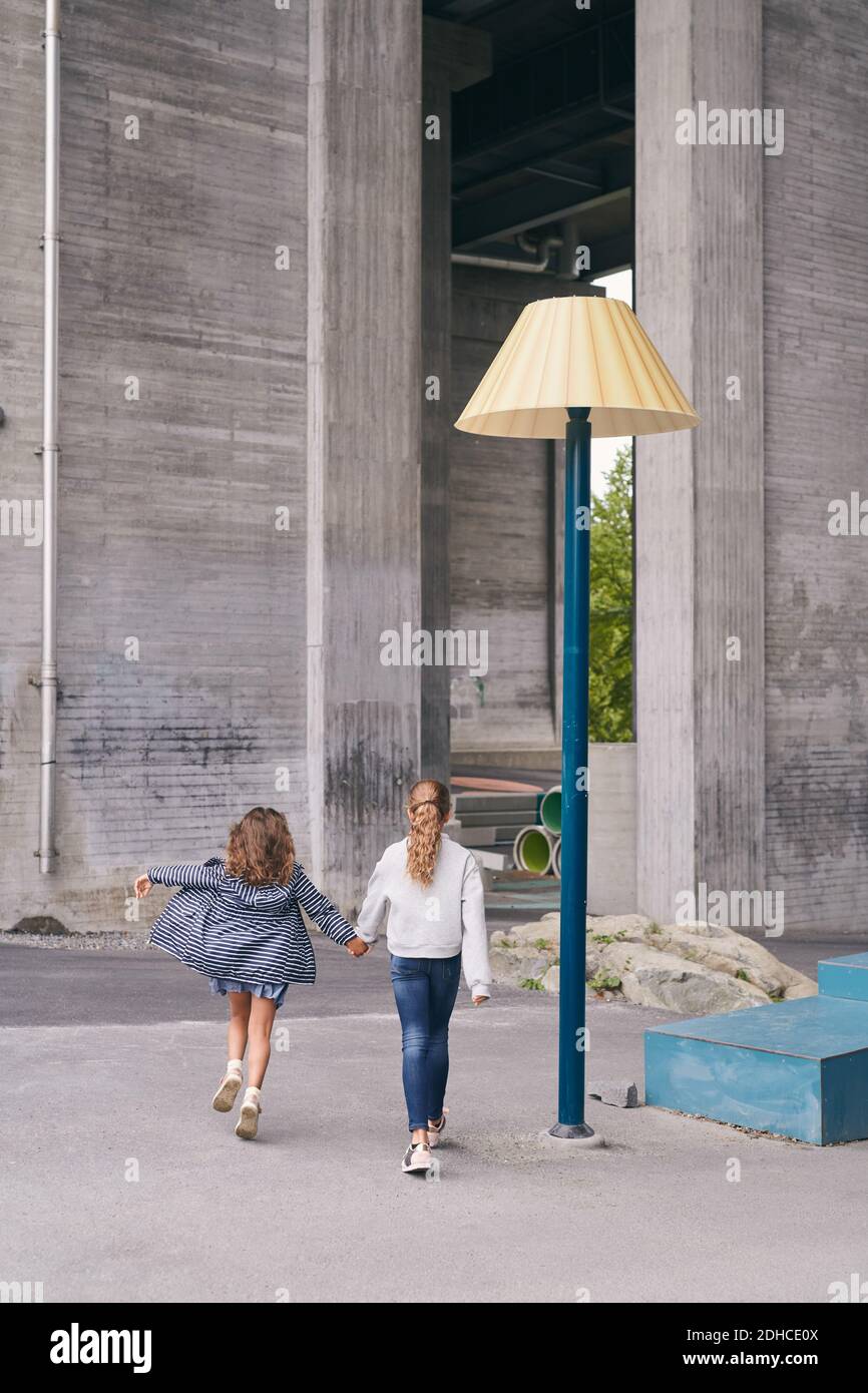 Vista posteriore delle sorelle spensierate che camminano sul sentiero della città Foto Stock