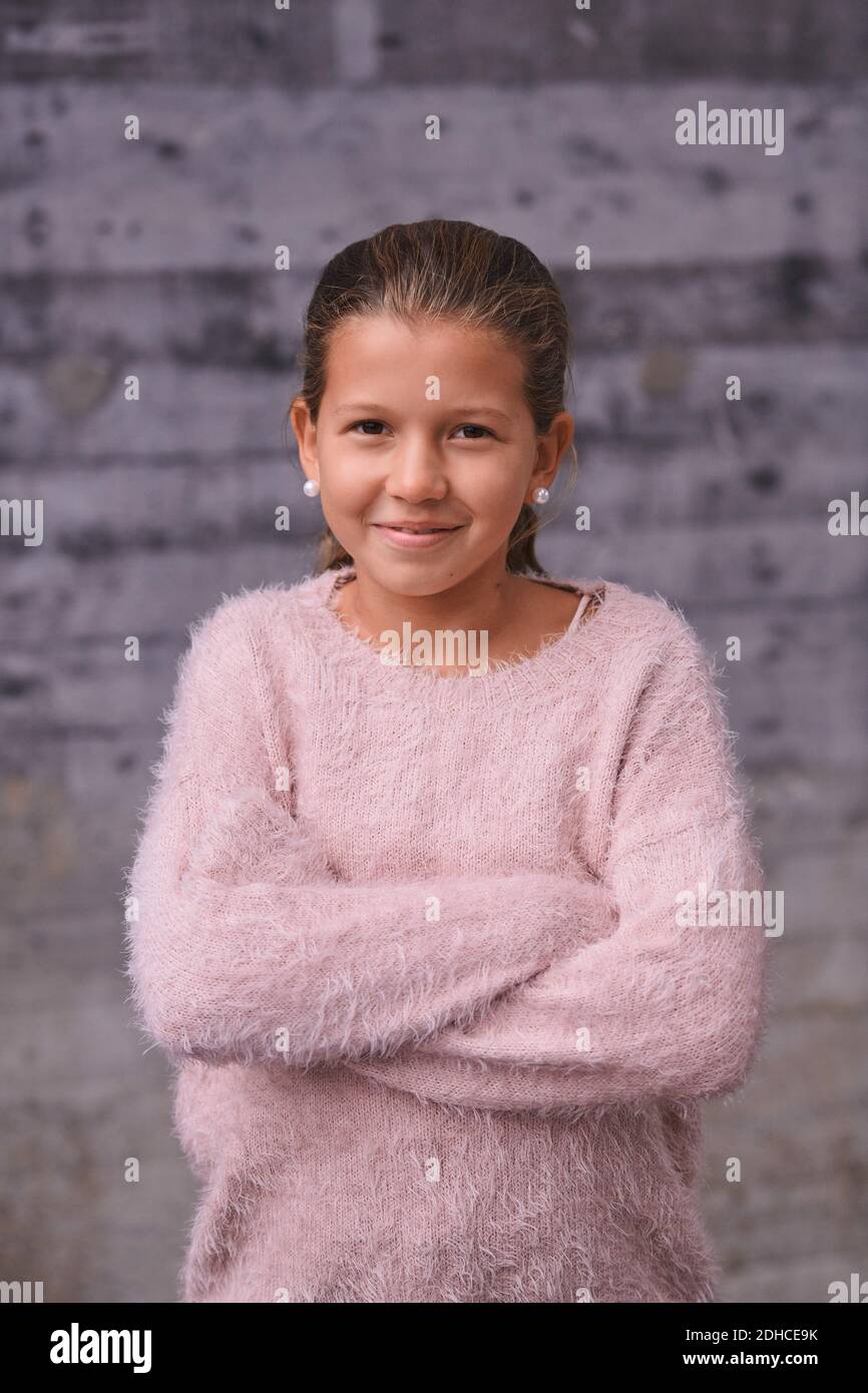 Ritratto di sorridente ragazza con le braccia incrociate in piedi all'aperto Foto Stock