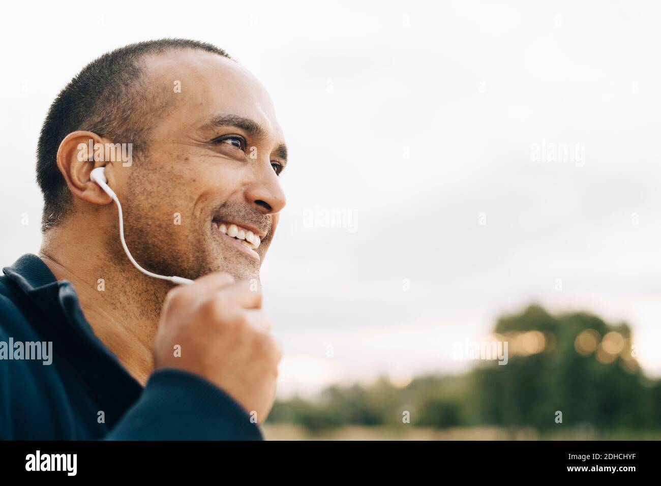 Primo piano di un uomo sorridente che parla con le cuffie mentre si guarda via Foto Stock