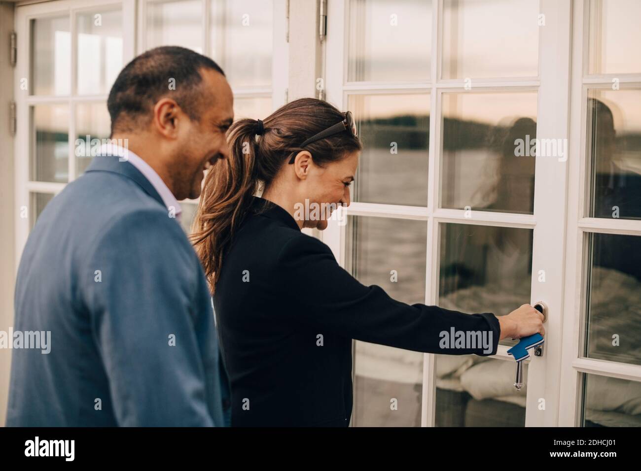 Una coppia matura sorridente che sbloccano la porta di vetro della villa per le vacanze Foto Stock