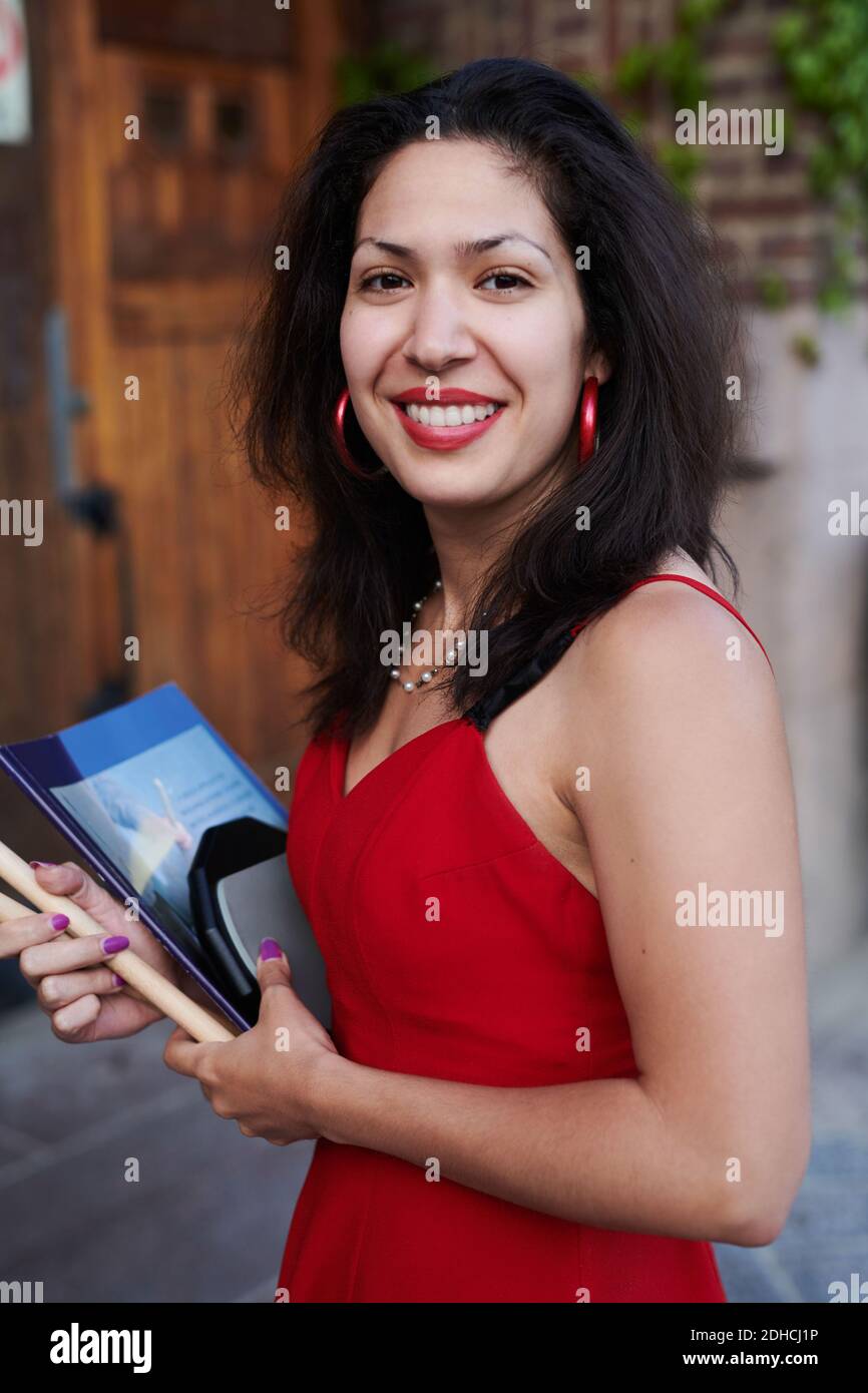 Ritratto di giovane donna sorridente con libro in piedi fuori lingua scuola Foto Stock