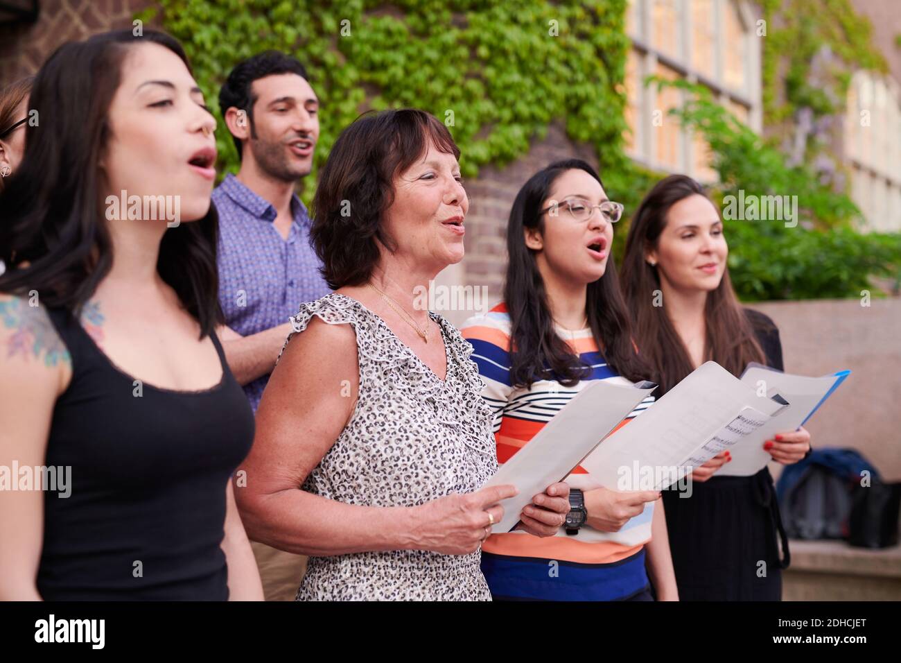 Cantanti corali multietnici che si esibiscono al di fuori della scuola di lingua Foto Stock