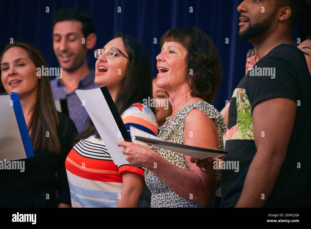 Cantanti corali multietnici che si esibiscono sul palco in auditorium Foto Stock