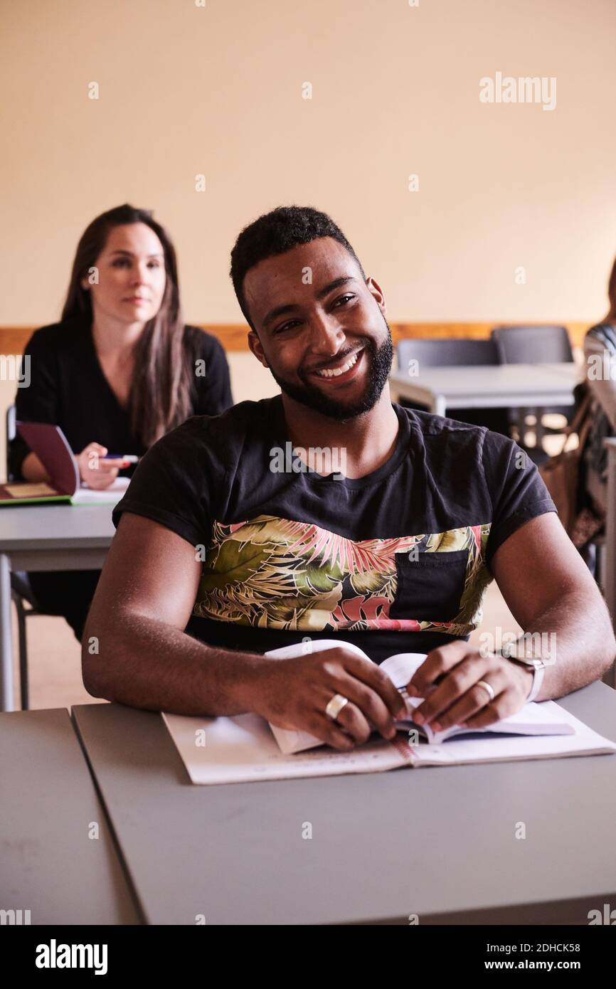 Studente sicuro che sorride mentre si siede alla scrivania nella scuola di lingua Foto Stock