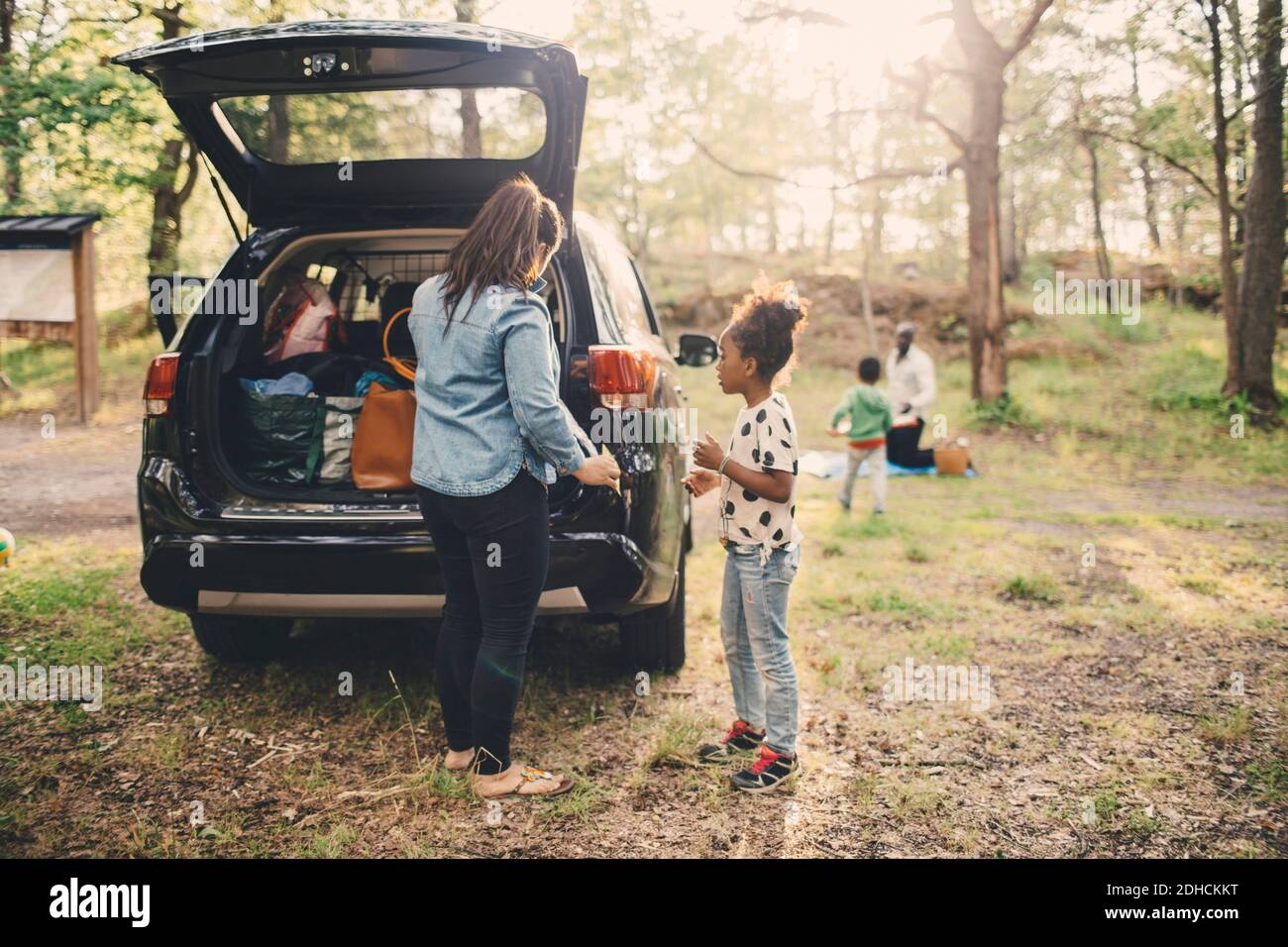Tutta la lunghezza di donna e figlia che scaricano i bagagli dall'impianto elettrico vano auto al parcheggio Foto Stock