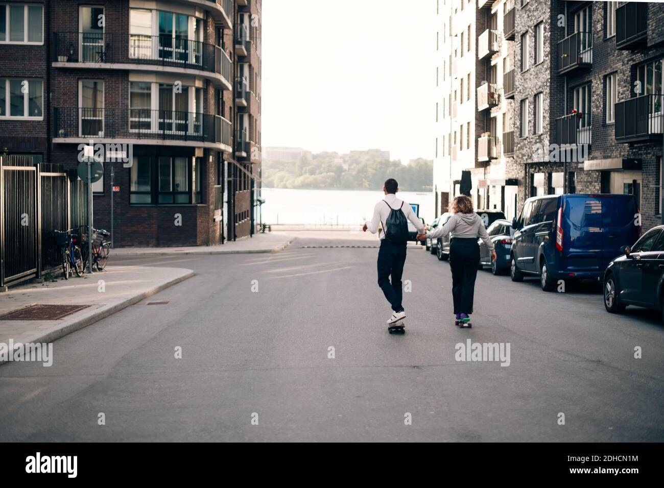 Tutta la lunghezza degli amici che skateboard insieme su strada in città Foto Stock