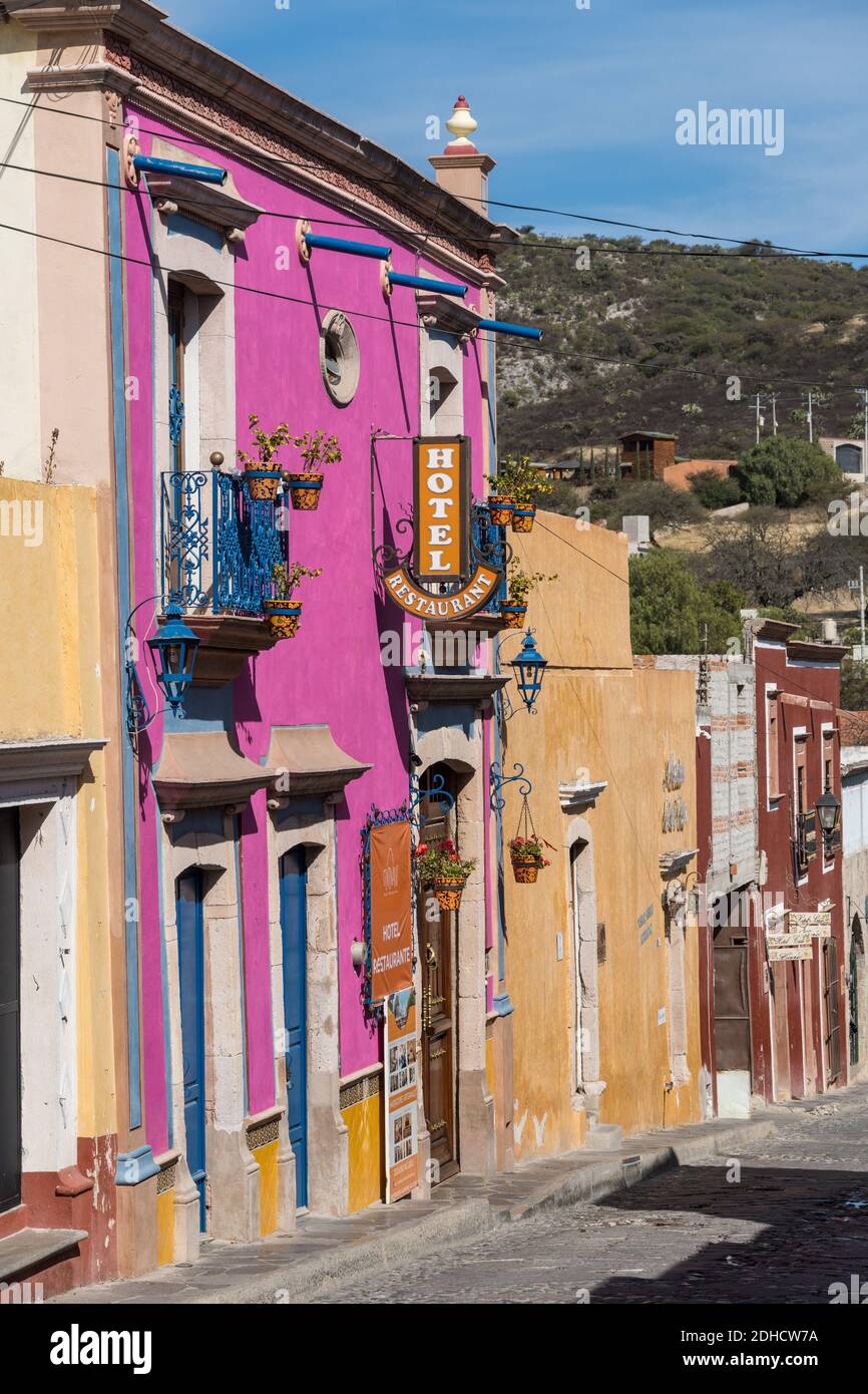 L'Hotel Centenario Centro, di colore rosa, è situato nel bellissimo villaggio coloniale di Bernal, Queretaro, Messico. Bernal è una pittoresca città coloniale conosciuta per la pena de Bernal, un monolito gigante che domina il piccolo villaggio è il terzo più alto del pianeta. Foto Stock