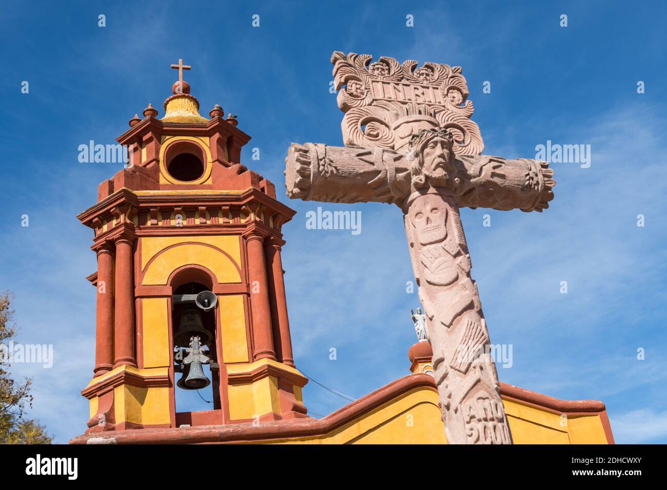 La chiesa Parroquia San Sebastian con croce decorativa e campanile nel bellissimo villaggio coloniale di Bernal, Queretaro, Messico. Bernal è una pittoresca città coloniale conosciuta per la pena de Bernal, un monolito gigante che domina il piccolo villaggio è il terzo più alto del pianeta. Foto Stock