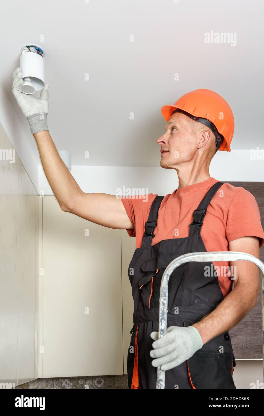 L'operatore sta installando un faretto a LED sul soffitto sospeso. Foto Stock