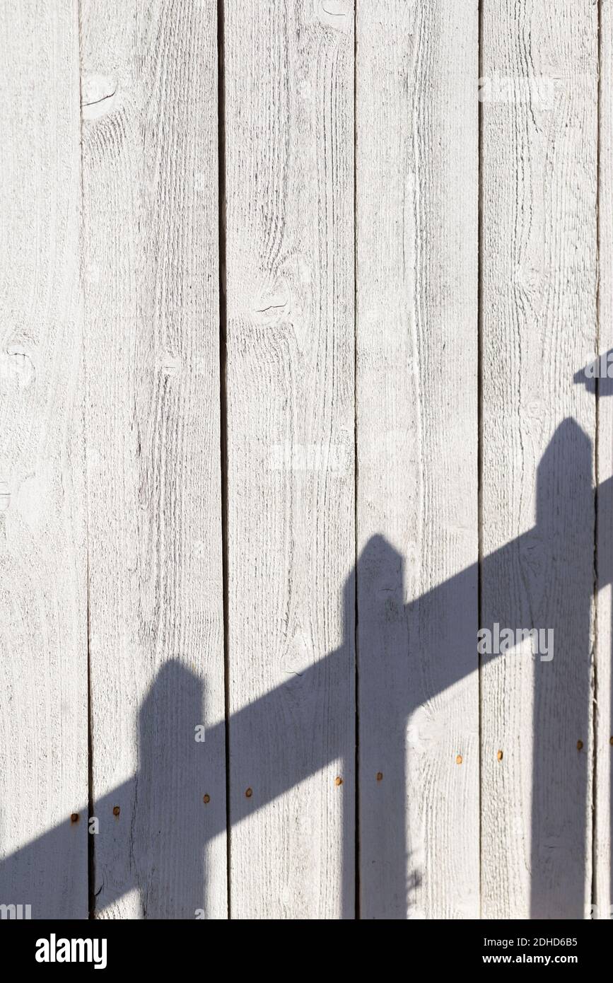 Una recinzione che getta un'ombra su un'altra recinzione. Foto Stock