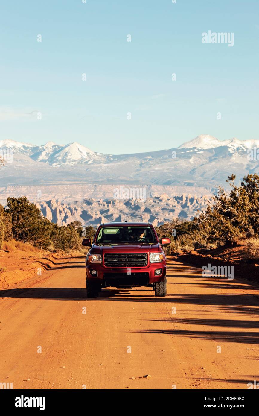 Camion rosso pick-up centrato in strada sterrata nel deserto vicino Moab, Utah Foto Stock