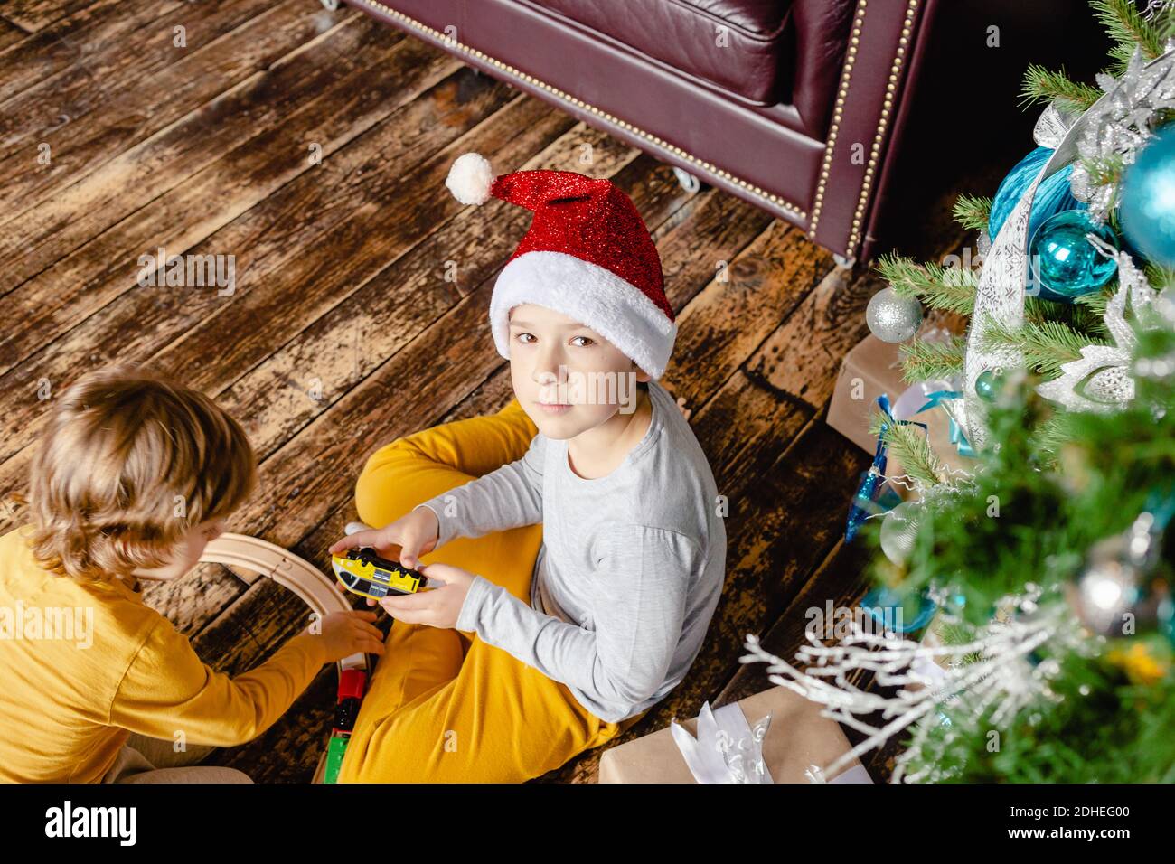 I bambini piccoli costruiscono la ferrovia e giocano con il treno giocattolo sotto l'albero di Natale. Bambini con regali di Natale. Tempo di Natale. Foto Stock