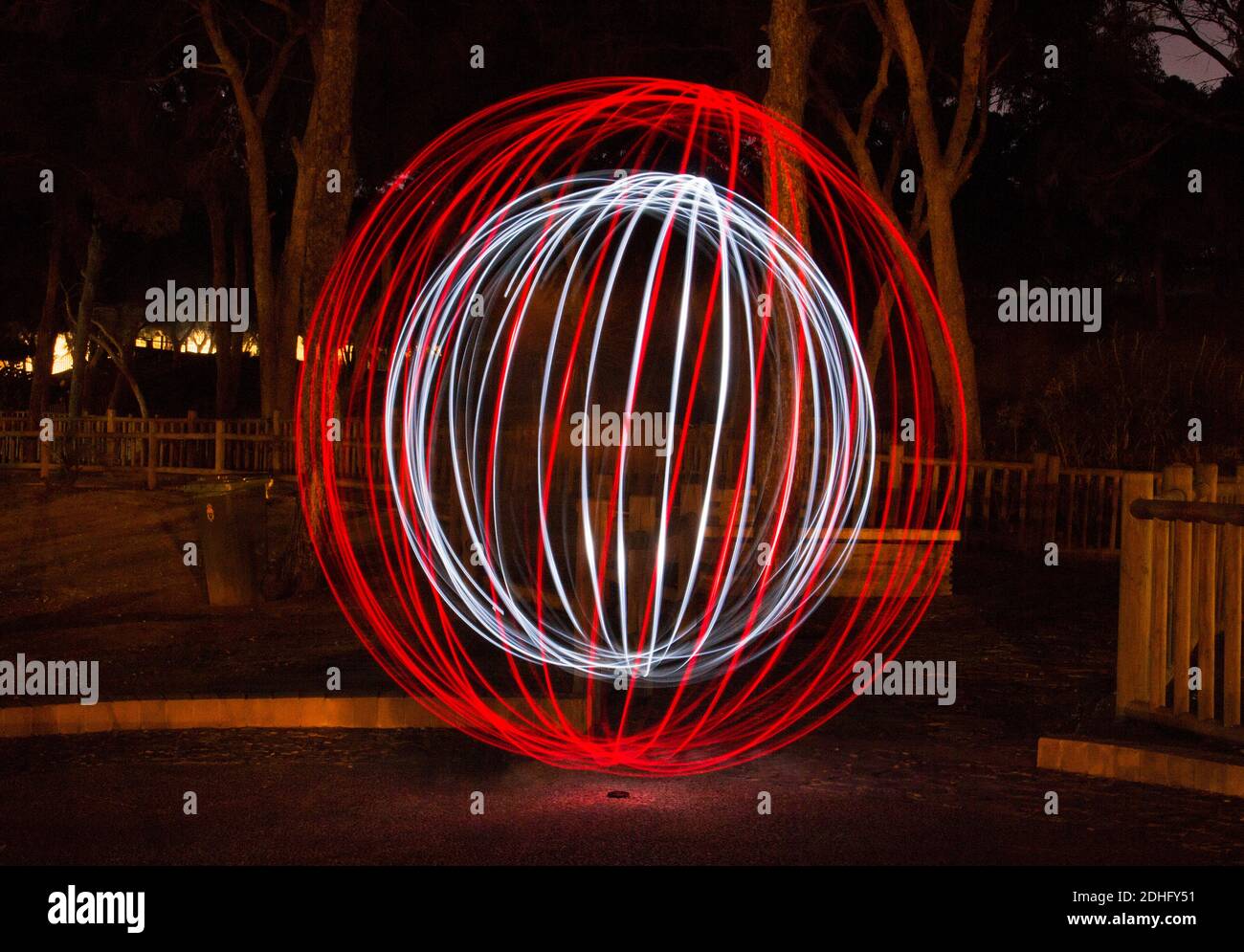 Sperimenta usando due torce nel parco per creare una palla di luce. La fotocamera con un otturatore aperto. Fotografato a Guardamar, Alicante, Spagna. Foto Stock